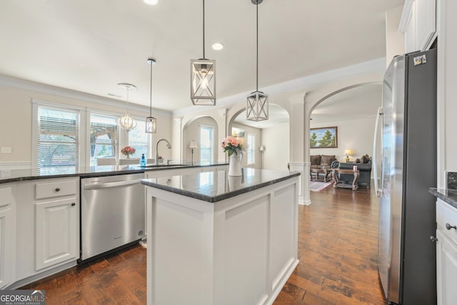 kitchen with white cabinetry, sink, decorative light fixtures, a kitchen island, and appliances with stainless steel finishes