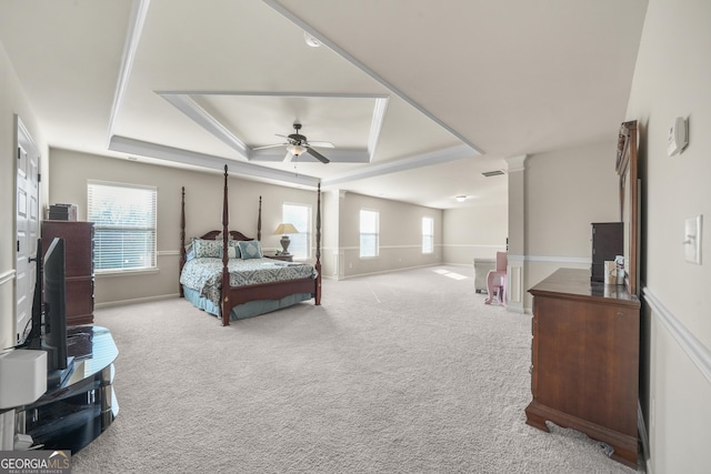 bedroom featuring a raised ceiling, multiple windows, ceiling fan, and light carpet