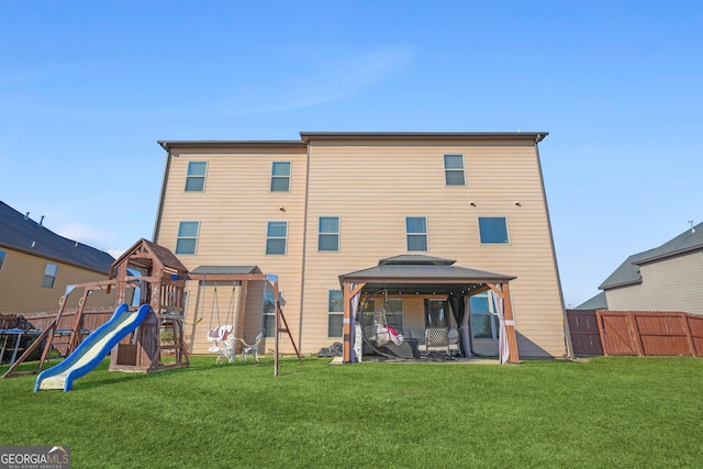 rear view of property with a gazebo, a playground, and a lawn