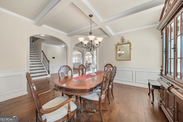 dining area with beam ceiling, ornamental molding, dark wood-type flooring, and an inviting chandelier