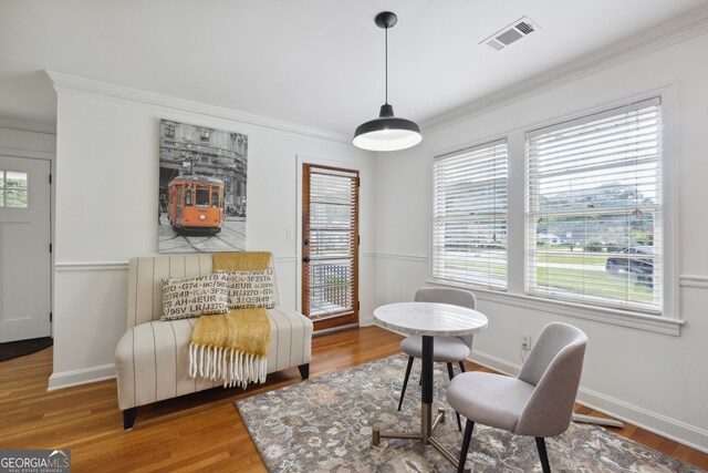 living area featuring a wealth of natural light, crown molding, and hardwood / wood-style flooring