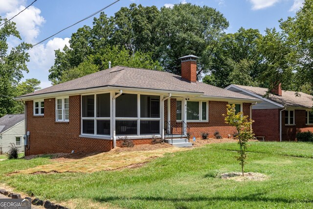 single story home featuring a sunroom and a front lawn