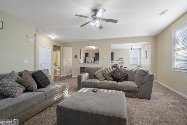 carpeted living room featuring ceiling fan with notable chandelier