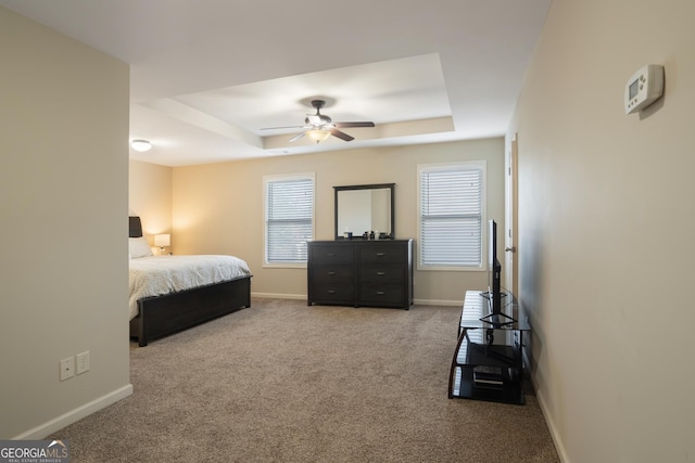 bedroom featuring a tray ceiling, ceiling fan, and light carpet