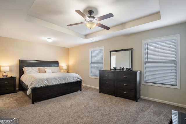 bedroom with light carpet, a raised ceiling, and ceiling fan