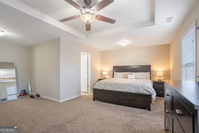 bedroom featuring light carpet, a raised ceiling, and ceiling fan