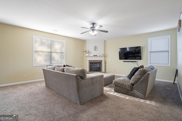 carpeted living room with a fireplace and ceiling fan