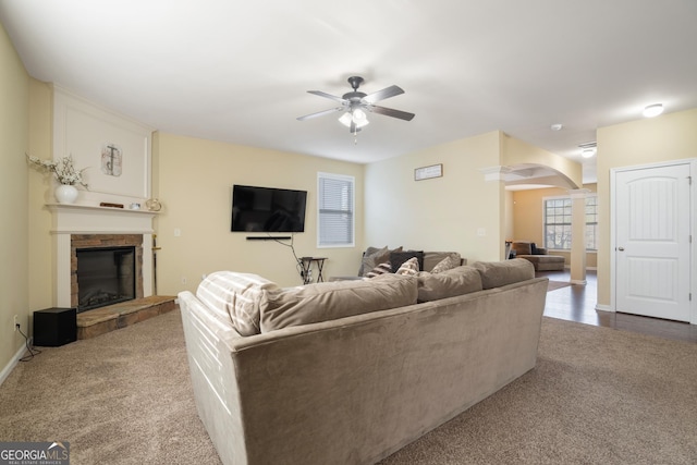 living room with carpet flooring, ceiling fan, and a fireplace