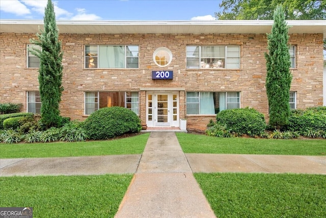 view of property featuring french doors and a front lawn