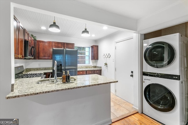 laundry room featuring sink, light hardwood / wood-style floors, and stacked washer / drying machine