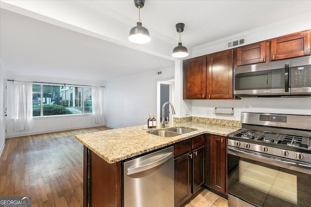 kitchen with sink, kitchen peninsula, stainless steel appliances, and hanging light fixtures