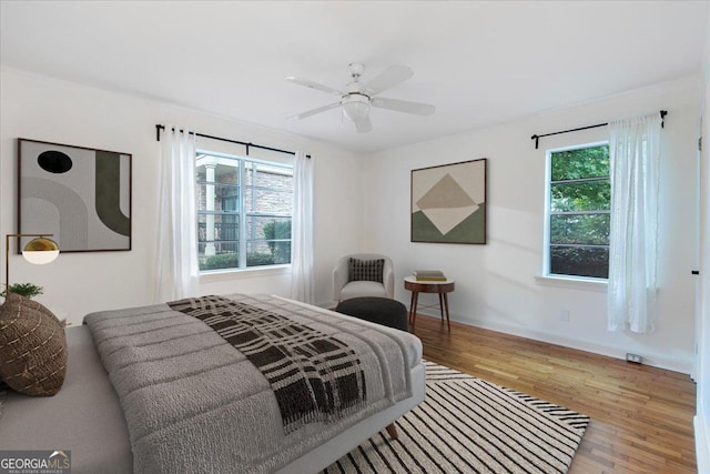 bedroom featuring hardwood / wood-style flooring, ceiling fan, and multiple windows