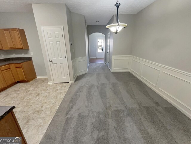 unfurnished dining area featuring light colored carpet and a textured ceiling