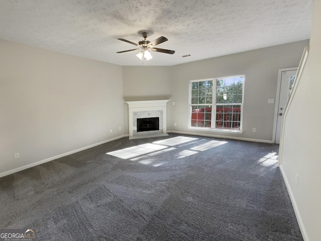 unfurnished living room featuring a high end fireplace, a textured ceiling, dark carpet, and ceiling fan