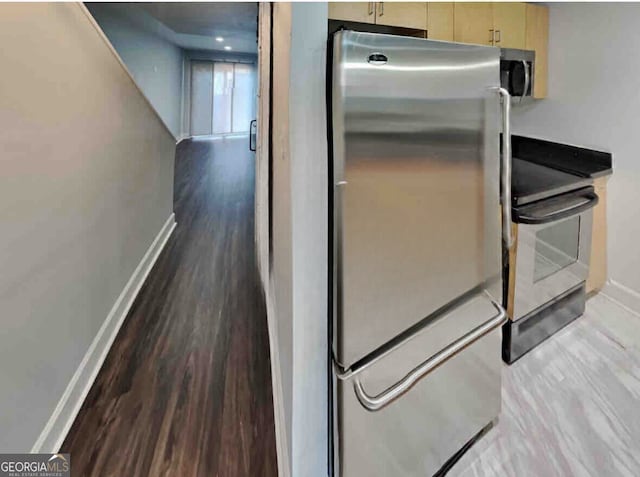 kitchen featuring light brown cabinets, stainless steel appliances, and wood-type flooring