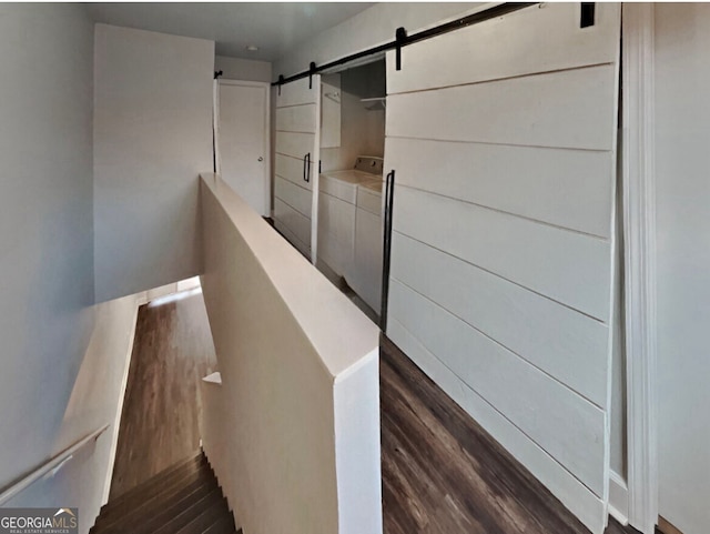 staircase featuring hardwood / wood-style flooring, a barn door, and washing machine and clothes dryer