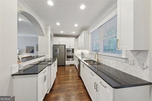 kitchen with decorative backsplash, stainless steel appliances, sink, dark stone countertops, and white cabinets