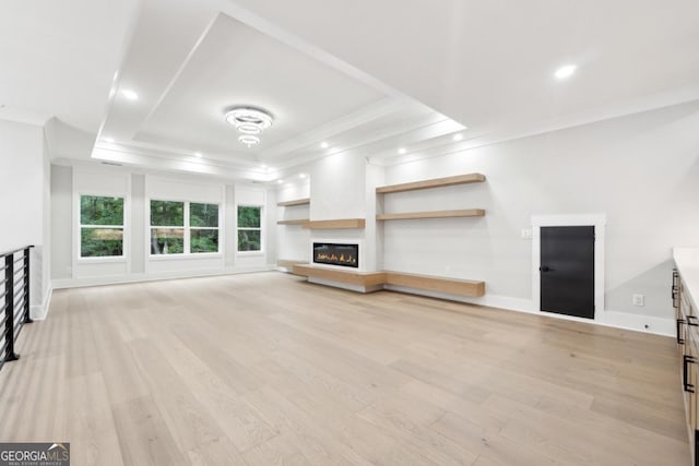 unfurnished living room with light wood-type flooring, ornamental molding, and a tray ceiling