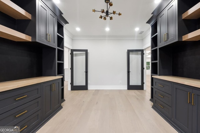 kitchen with pendant lighting, crown molding, light wood-type flooring, a notable chandelier, and butcher block counters