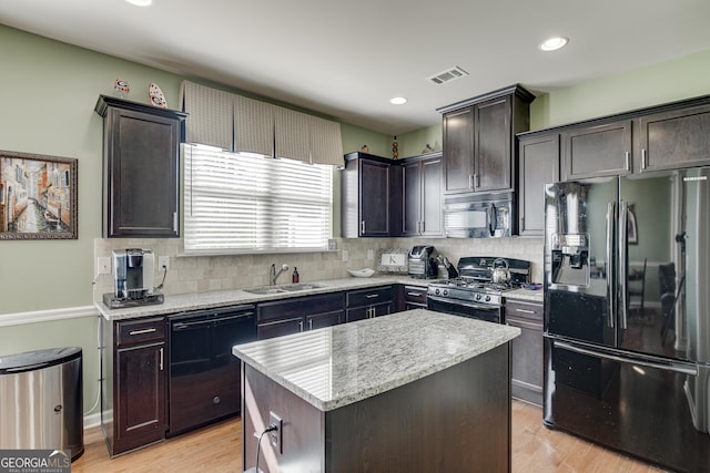 kitchen featuring a center island, black appliances, sink, light hardwood / wood-style flooring, and dark brown cabinetry