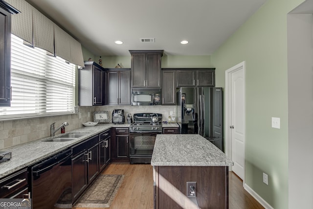 kitchen featuring decorative backsplash, a center island, black appliances, and light hardwood / wood-style floors