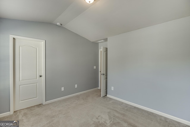 carpeted spare room with vaulted ceiling