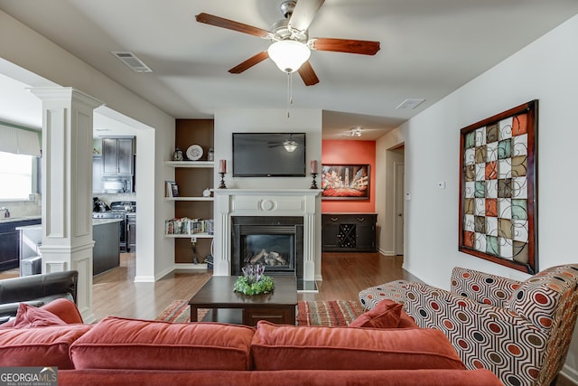 living room featuring built in shelves, ceiling fan, and light hardwood / wood-style floors