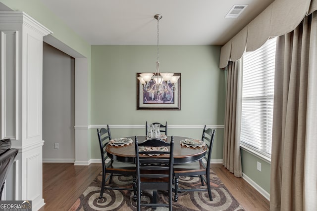 dining room featuring decorative columns, a chandelier, and hardwood / wood-style flooring