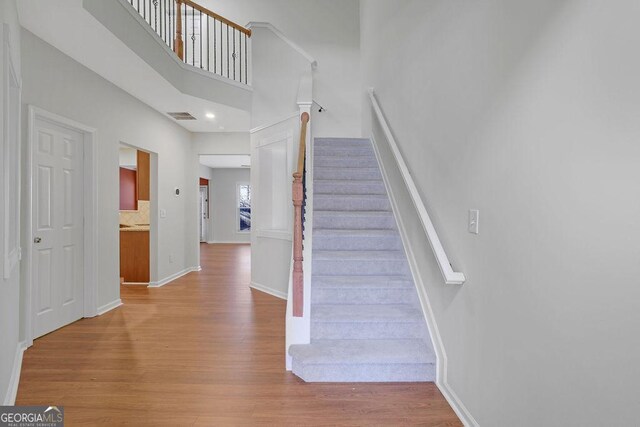 stairs with wood-type flooring and a towering ceiling