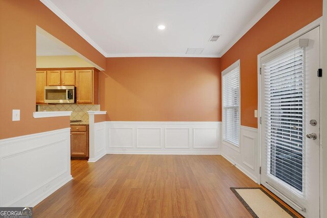 interior space with light hardwood / wood-style flooring, crown molding, light brown cabinets, and tasteful backsplash