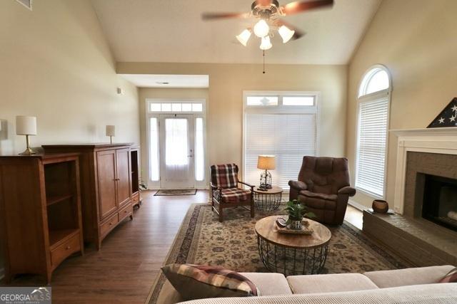 living room with ceiling fan, dark hardwood / wood-style flooring, and high vaulted ceiling