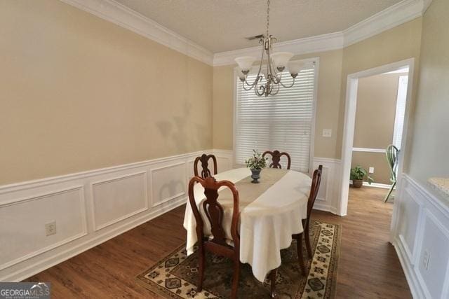 dining space featuring dark wood-type flooring, crown molding, and a chandelier