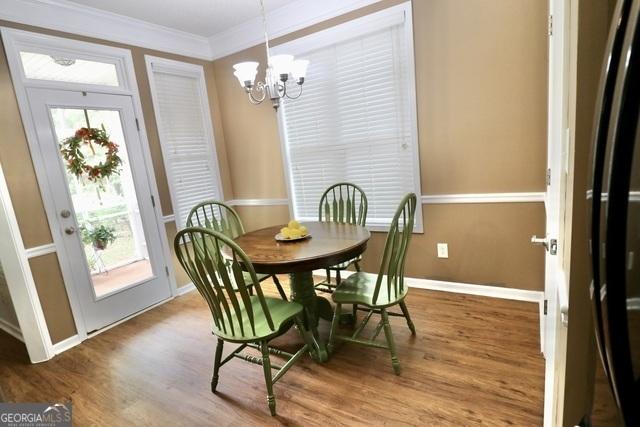 dining space featuring hardwood / wood-style floors, an inviting chandelier, and ornamental molding