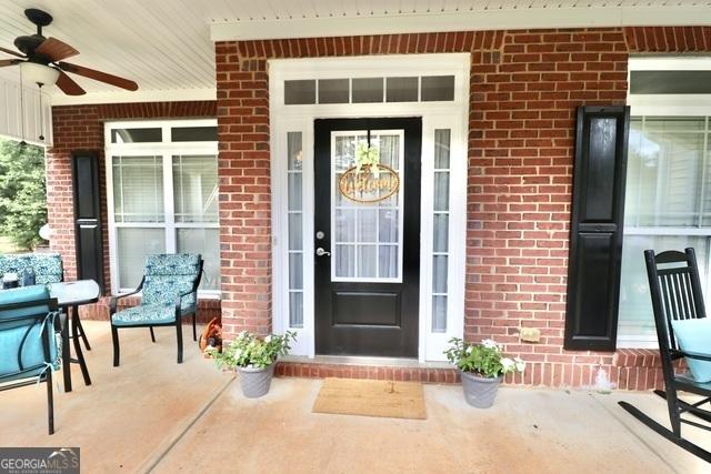 doorway to property with ceiling fan and covered porch