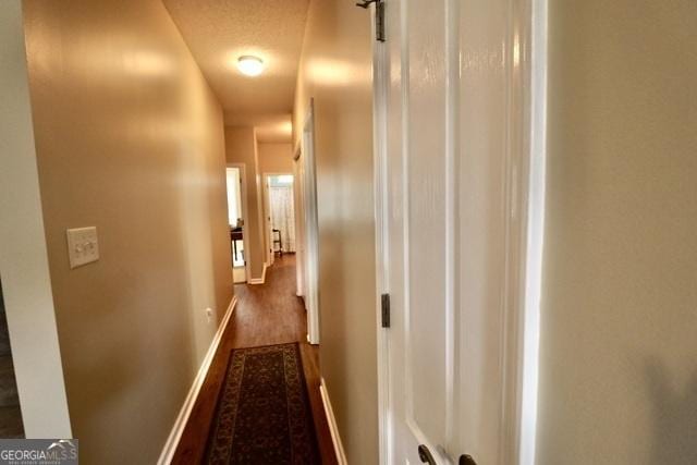 hall with dark hardwood / wood-style floors and a textured ceiling