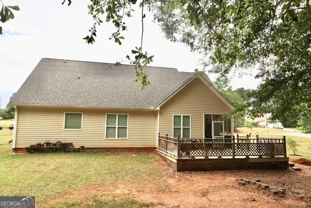 back of property with a wooden deck and a yard