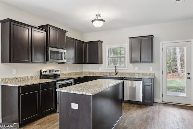 kitchen featuring appliances with stainless steel finishes, dark brown cabinets, sink, hardwood / wood-style floors, and a kitchen island