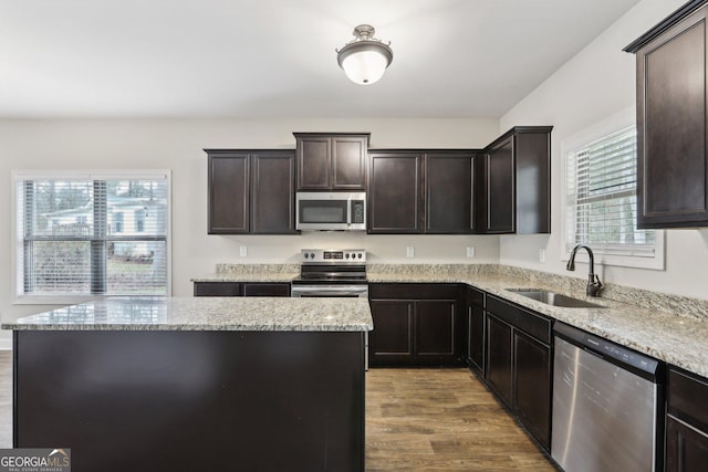 kitchen featuring dark brown cabinets, stainless steel appliances, sink, hardwood / wood-style floors, and a center island