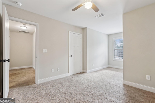 spare room with ceiling fan and light colored carpet