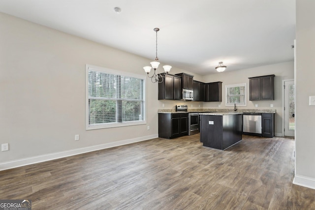 kitchen with a center island, stainless steel appliances, dark hardwood / wood-style floors, a notable chandelier, and decorative light fixtures