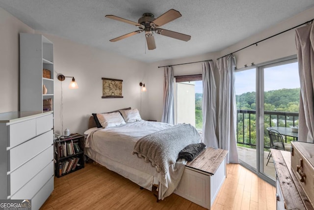 bedroom with ceiling fan, light wood-type flooring, a textured ceiling, and access to outside