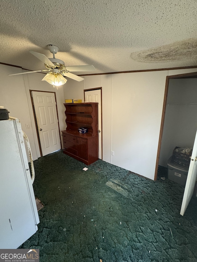 interior space featuring dark colored carpet, a textured ceiling, white refrigerator, and ceiling fan