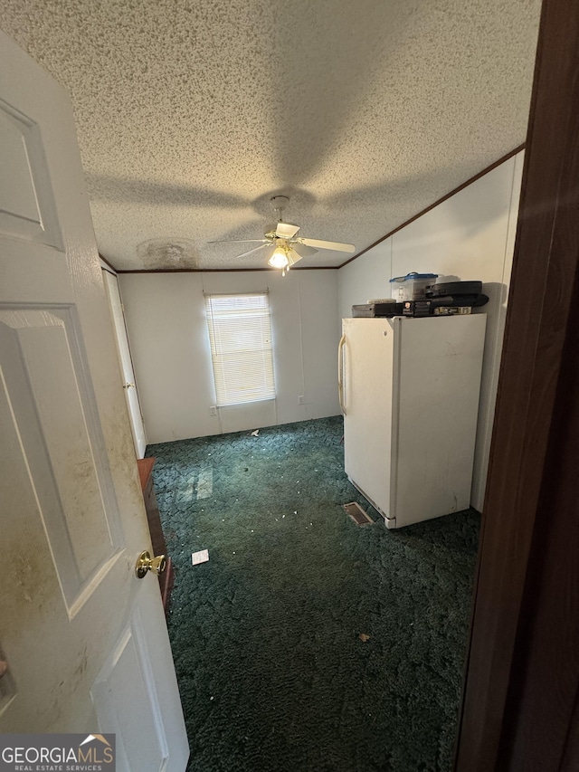 spare room with dark colored carpet, a textured ceiling, and ceiling fan