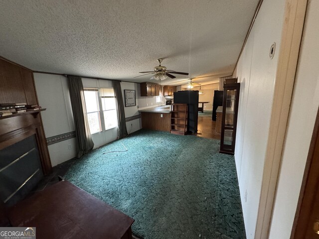 unfurnished living room with ceiling fan, dark carpet, and a textured ceiling