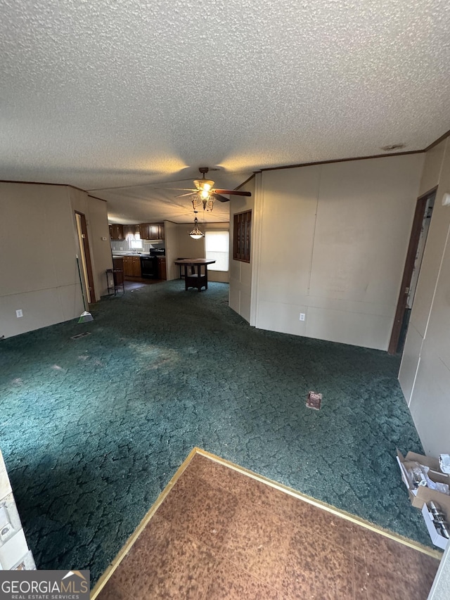 unfurnished living room with ceiling fan, dark carpet, and a textured ceiling