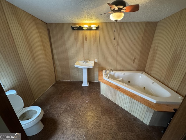 bathroom featuring a washtub, a textured ceiling, ceiling fan, toilet, and wood walls