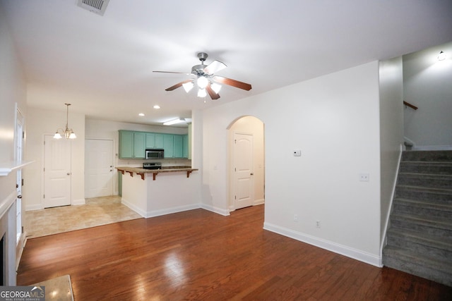 unfurnished living room with ceiling fan with notable chandelier and dark hardwood / wood-style floors