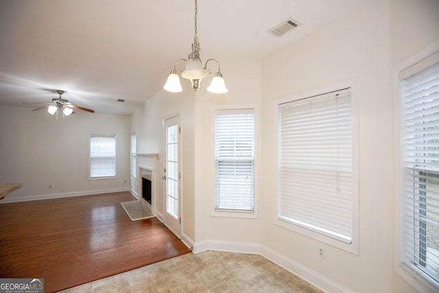 unfurnished living room with ceiling fan with notable chandelier and wood-type flooring