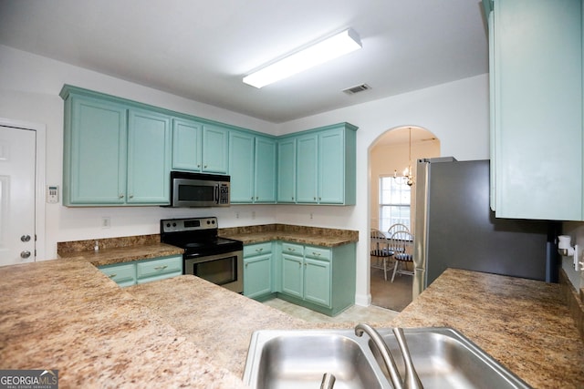 kitchen with sink, appliances with stainless steel finishes, and an inviting chandelier