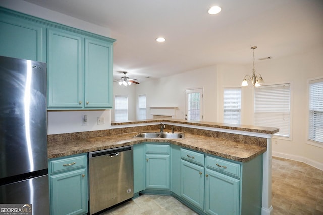 kitchen with pendant lighting, ceiling fan with notable chandelier, sink, kitchen peninsula, and stainless steel appliances